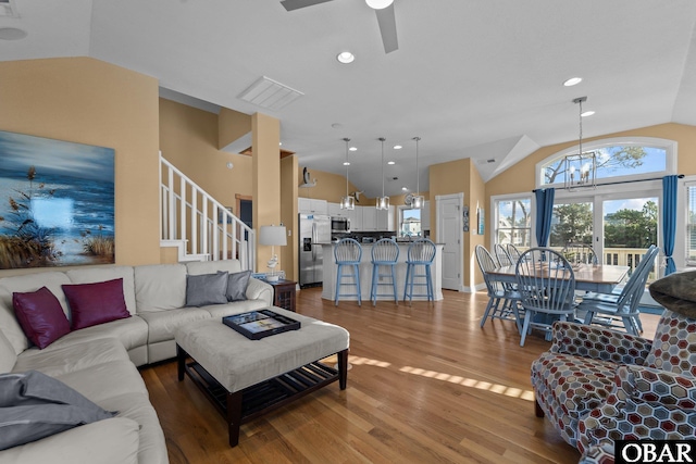 living area with lofted ceiling, recessed lighting, visible vents, wood finished floors, and stairs