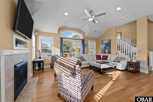 living area featuring lofted ceiling, a tile fireplace, recessed lighting, visible vents, and light wood-style floors