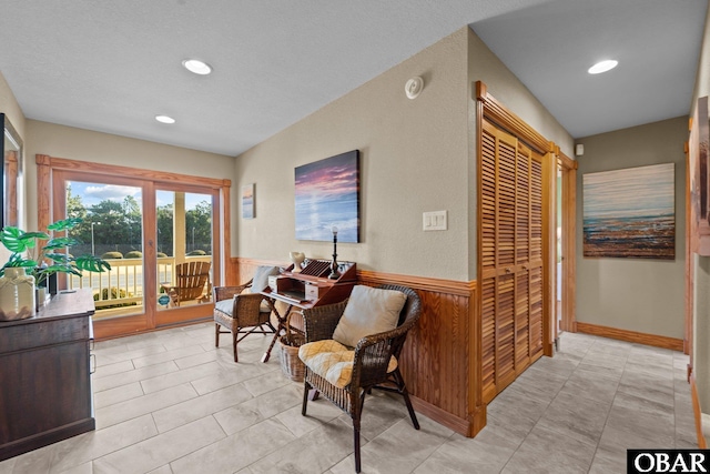 living area with recessed lighting, wainscoting, and wooden walls