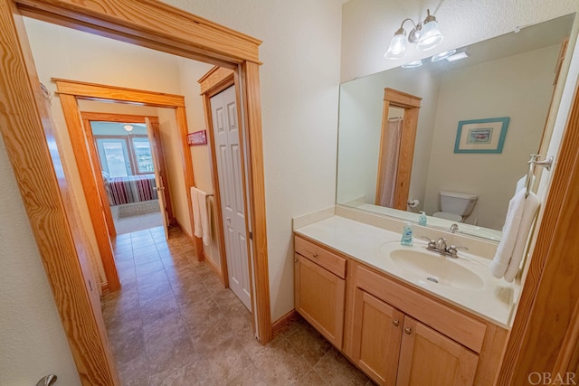 bathroom featuring toilet, vanity, and baseboards