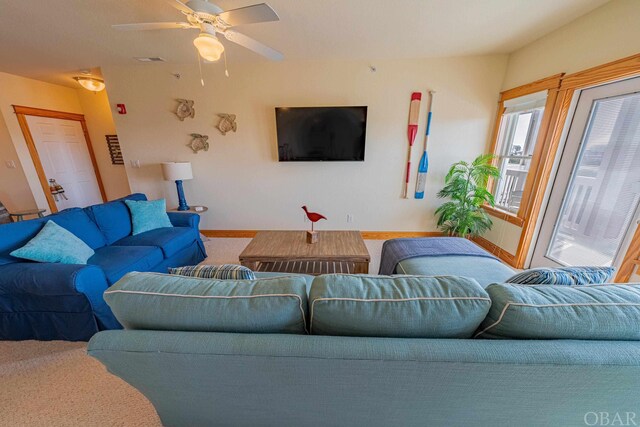 carpeted living area with a ceiling fan and baseboards