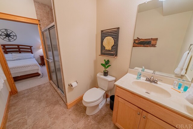 ensuite bathroom with connected bathroom, toilet, vanity, baseboards, and a shower stall