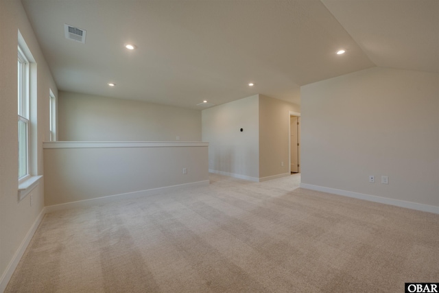 spare room featuring recessed lighting, lofted ceiling, light colored carpet, visible vents, and baseboards