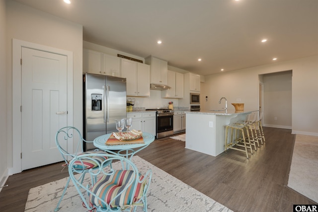 kitchen featuring recessed lighting, under cabinet range hood, stainless steel appliances, dark wood-type flooring, and a sink