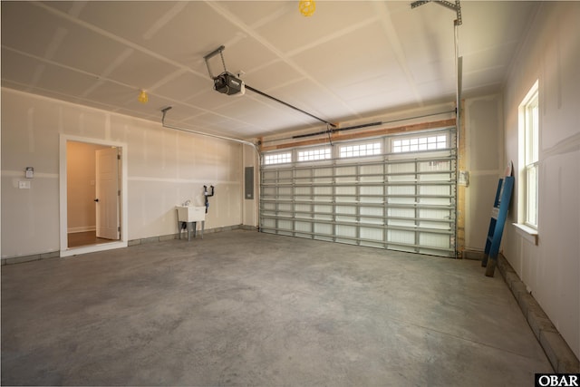 garage featuring a garage door opener, electric panel, and a sink