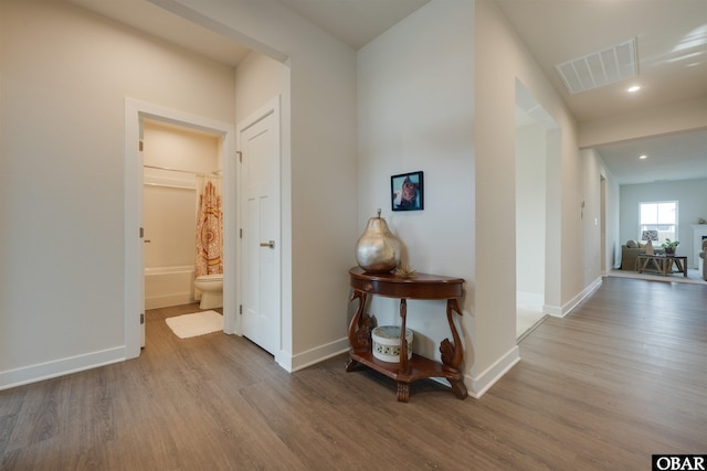 hall with recessed lighting, visible vents, baseboards, and wood finished floors