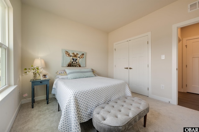 bedroom with light colored carpet, a closet, visible vents, and baseboards