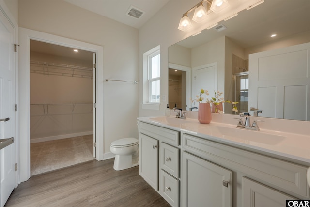 bathroom featuring visible vents, a sink, a shower stall, and wood finished floors