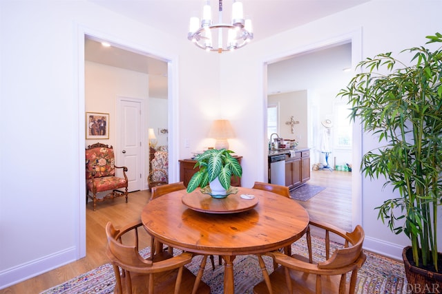 dining room with a notable chandelier, baseboards, and light wood-style floors