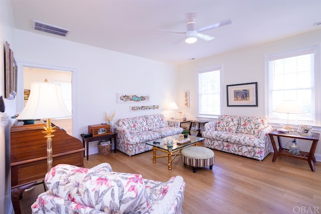 living area featuring light wood-type flooring, ceiling fan, and visible vents