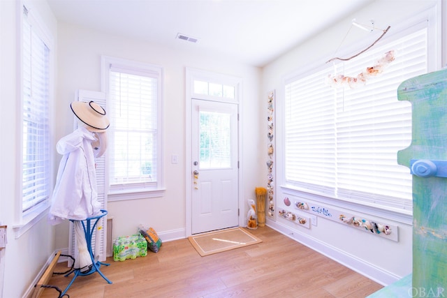 doorway to outside featuring light wood-type flooring, visible vents, and baseboards