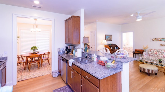 kitchen with visible vents, light wood-style flooring, stainless steel dishwasher, brown cabinetry, and a sink