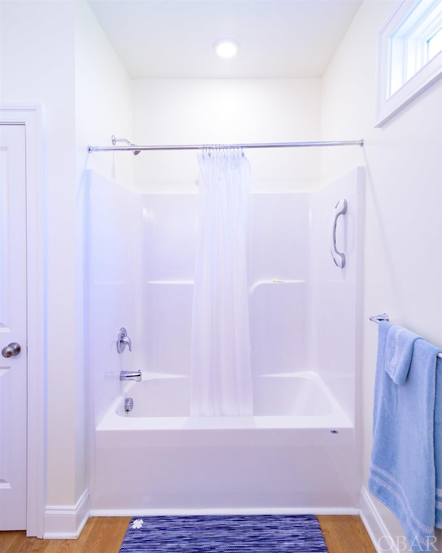 bathroom with shower / bathtub combination with curtain and wood finished floors