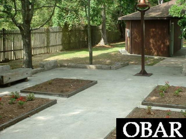 view of yard with a garden, fence, an outbuilding, and a patio