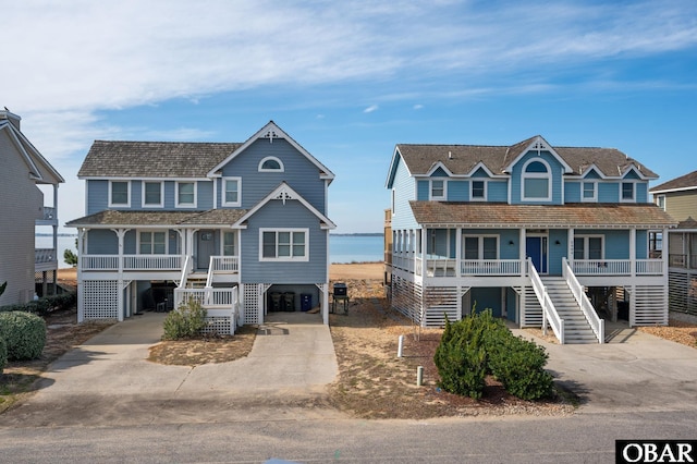 coastal inspired home with a carport, stairway, covered porch, and concrete driveway