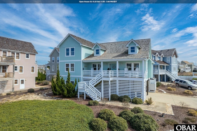 back of property with stairway, a residential view, covered porch, and concrete driveway