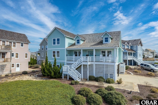 rear view of house featuring a porch, stairway, a residential view, and driveway