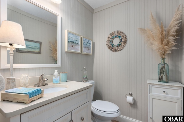 half bathroom featuring toilet, vanity, and baseboards