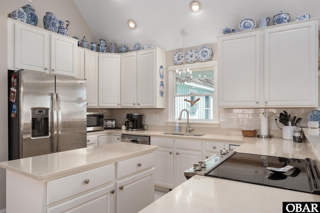 kitchen featuring lofted ceiling, a sink, decorative backsplash, stainless steel appliances, and white cabinetry