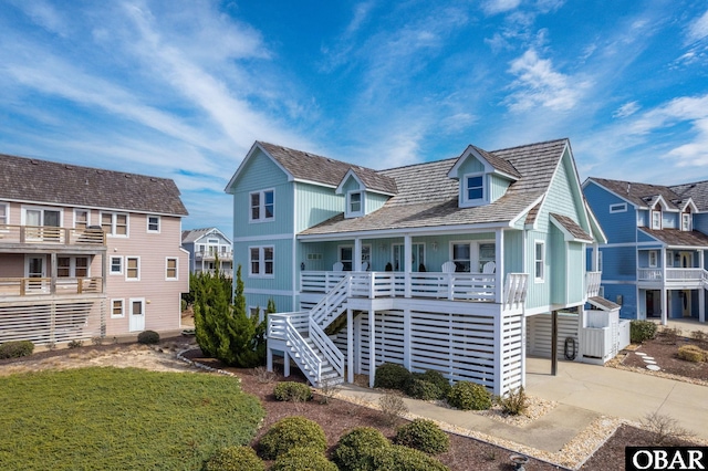 view of front of home featuring stairway, a residential view, board and batten siding, covered porch, and concrete driveway