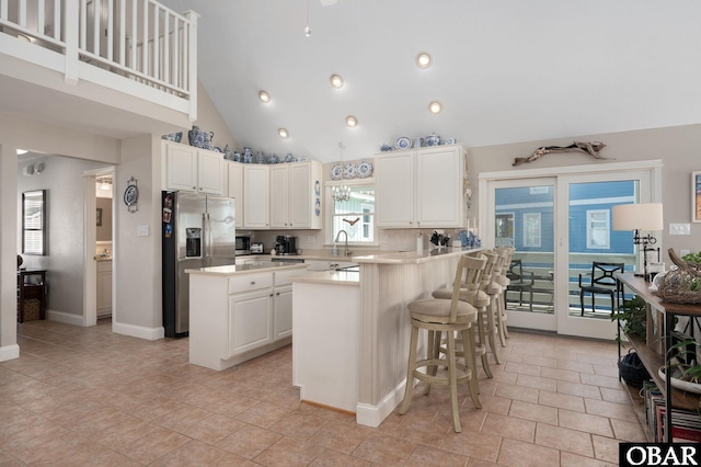 kitchen with a kitchen island, a breakfast bar area, light countertops, a peninsula, and stainless steel fridge