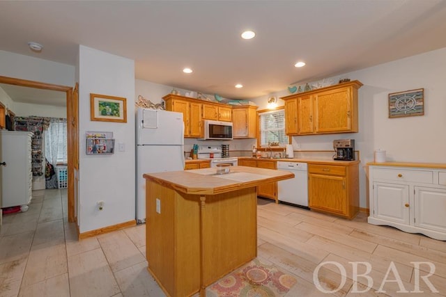 kitchen featuring light wood-style flooring, recessed lighting, white appliances, a kitchen island, and tile counters