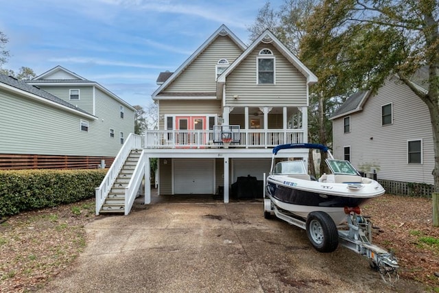 back of property with driveway, an attached garage, and stairs