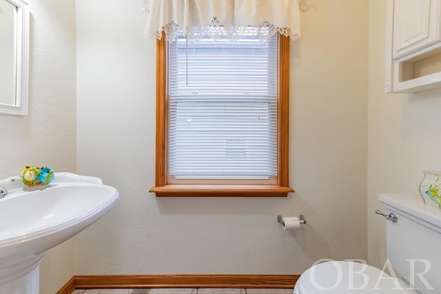 bathroom featuring a sink, toilet, and baseboards