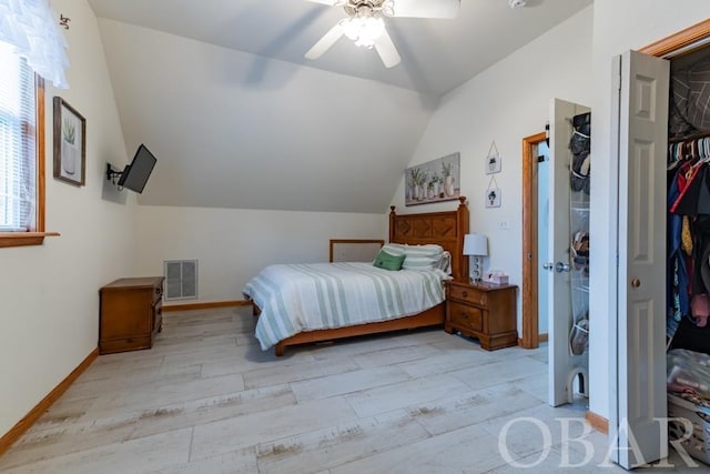 bedroom with baseboards, visible vents, lofted ceiling, light wood-type flooring, and a closet