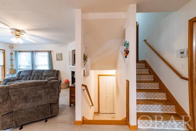 stairs featuring ceiling fan, a fireplace, and tile patterned floors