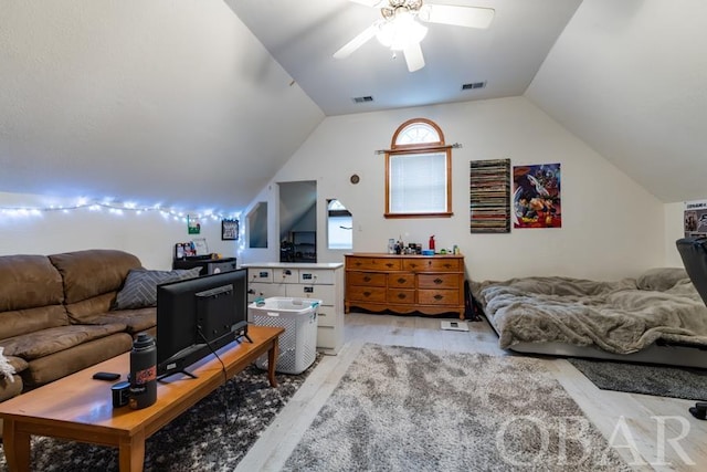 living room featuring lofted ceiling, light wood finished floors, visible vents, and a ceiling fan