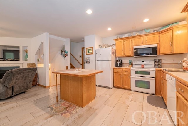 kitchen featuring light countertops, light wood-style floors, open floor plan, a sink, and white appliances