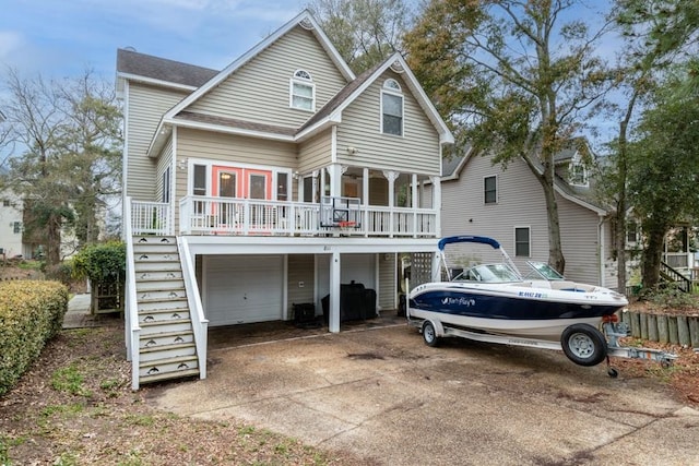 back of property with a garage, driveway, and stairway