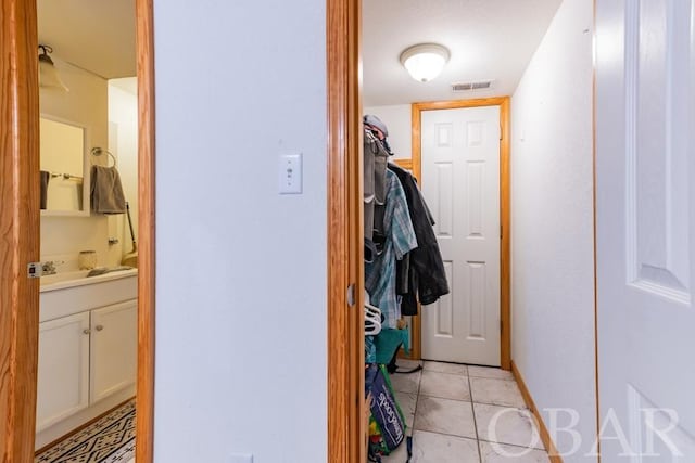 corridor with light tile patterned flooring, visible vents, and baseboards