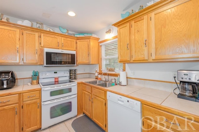 kitchen featuring light tile patterned floors, recessed lighting, white appliances, a sink, and tile counters