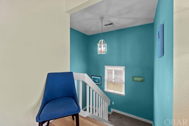 stairway with a healthy amount of sunlight, visible vents, baseboards, and wood finished floors