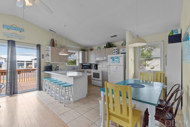 kitchen with pendant lighting, lofted ceiling, white appliances, and light countertops