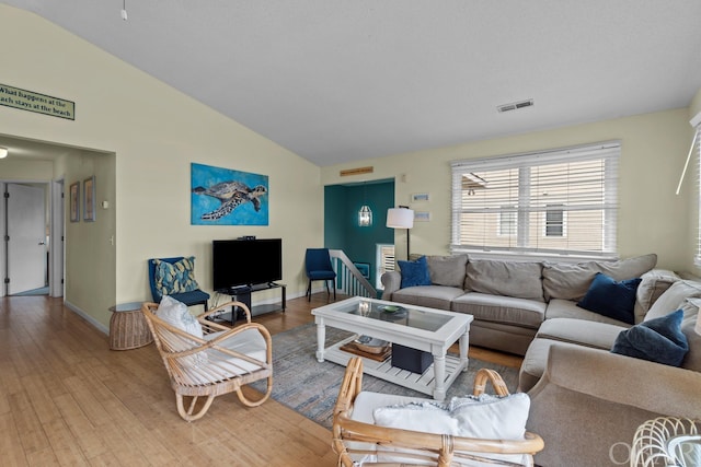 living area featuring vaulted ceiling, wood finished floors, visible vents, and baseboards