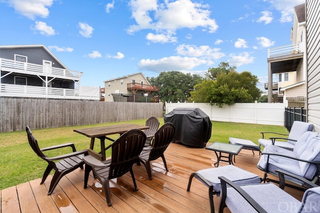 wooden deck with outdoor dining area, a fenced backyard, a yard, and area for grilling