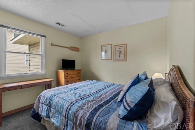 carpeted bedroom featuring a textured ceiling, visible vents, and baseboards