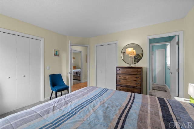 bedroom featuring a textured ceiling and multiple closets