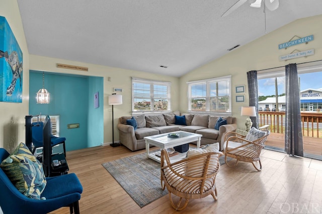 living room featuring a healthy amount of sunlight, visible vents, vaulted ceiling, and light wood finished floors