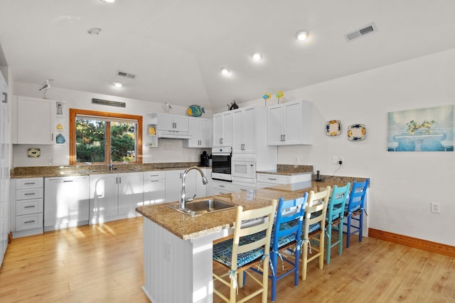 kitchen featuring wall oven, under cabinet range hood, a sink, visible vents, and stainless steel dishwasher