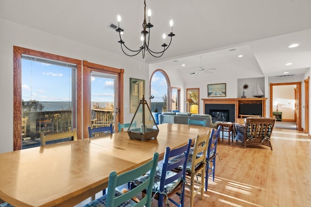 dining space with light wood-style floors, a glass covered fireplace, a healthy amount of sunlight, and recessed lighting