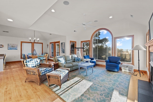 living area with lofted ceiling, light wood-style flooring, a fireplace, and visible vents