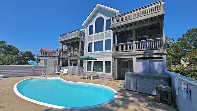 rear view of property with a fenced in pool, a patio area, and a hot tub