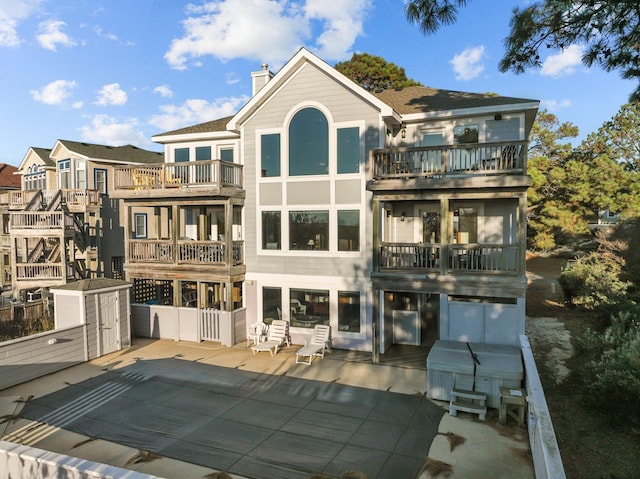 rear view of property featuring a chimney, a patio area, and a balcony