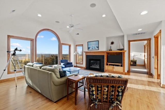 living room featuring a fireplace with flush hearth, vaulted ceiling, and wood finished floors