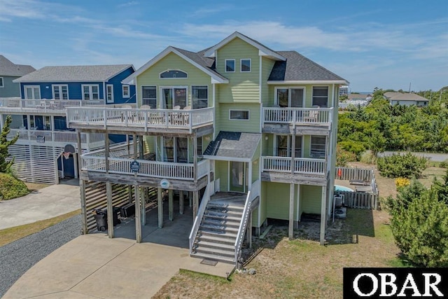 rear view of property with a balcony, a residential view, stairway, roof with shingles, and a carport