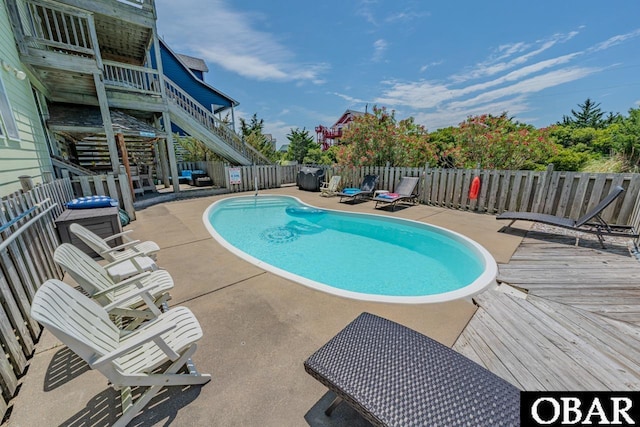 view of swimming pool featuring a fenced in pool, a patio area, fence private yard, a wooden deck, and stairs